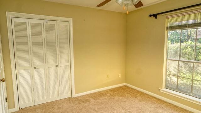 unfurnished bedroom with baseboards, ceiling fan, a closet, and light colored carpet