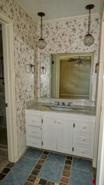 bathroom with crown molding, vanity, and wallpapered walls