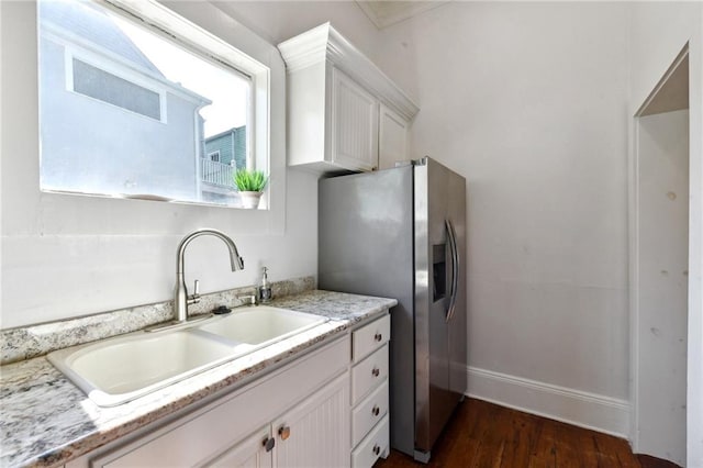 kitchen featuring sink, dark wood-type flooring, light stone counters, stainless steel refrigerator with ice dispenser, and white cabinetry