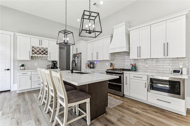 kitchen featuring custom range hood, stainless steel appliances, light wood-type flooring, and tasteful backsplash