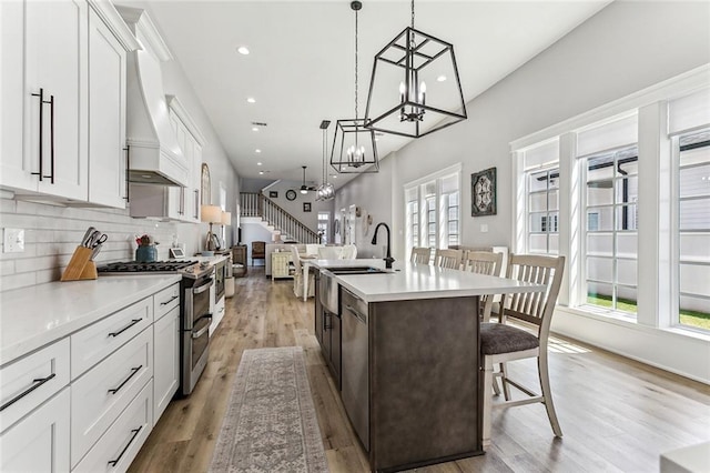 kitchen with a wealth of natural light, light hardwood / wood-style flooring, an island with sink, and double oven range