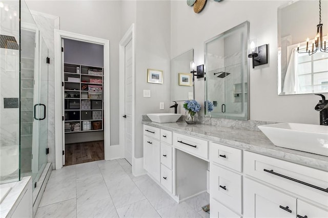 bathroom with tile patterned flooring, a shower with door, a notable chandelier, and vanity