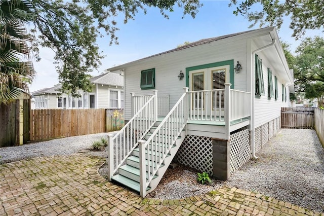 view of front of home featuring a patio, stairway, and a fenced backyard