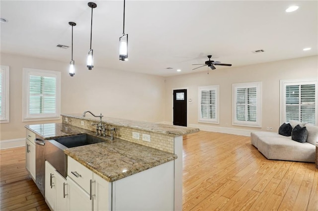 kitchen featuring ceiling fan, light stone countertops, pendant lighting, white cabinets, and light wood-type flooring