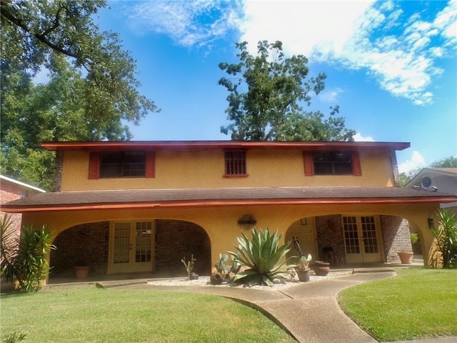 rear view of house featuring a yard, french doors, and stucco siding