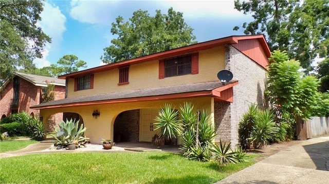 view of front of property featuring brick siding, stucco siding, and a front yard