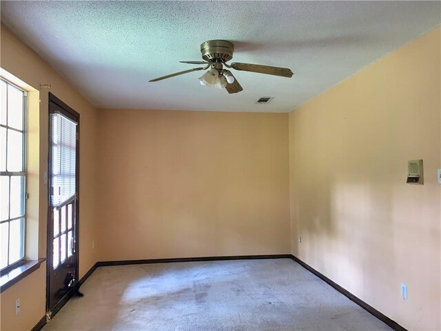 carpeted spare room featuring ceiling fan and a textured ceiling