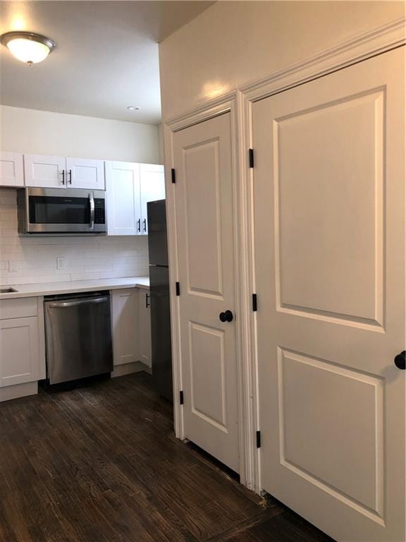 kitchen with white cabinetry, backsplash, stainless steel appliances, and dark hardwood / wood-style floors