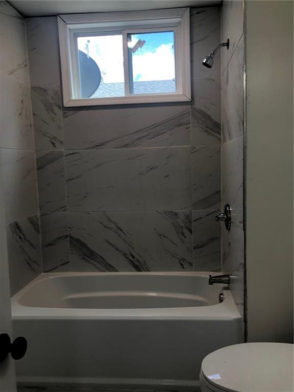 bathroom with tiled shower / bath combo and toilet