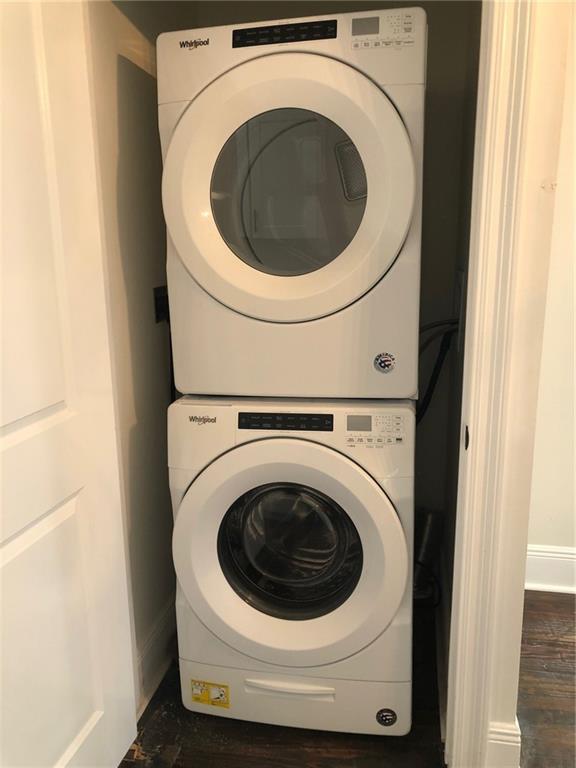 washroom featuring stacked washing maching and dryer and dark hardwood / wood-style floors