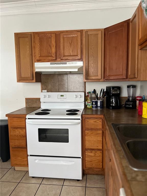 kitchen with light tile patterned floors, sink, crown molding, and electric stove