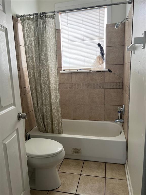 bathroom featuring tile patterned flooring, shower / bathtub combination with curtain, and toilet