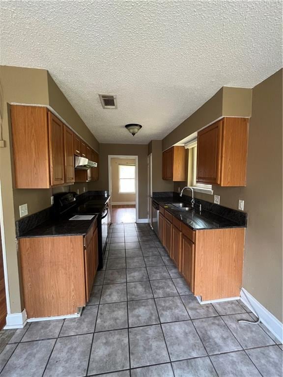 kitchen featuring black range with electric stovetop, dishwashing machine, tile patterned floors, and a textured ceiling