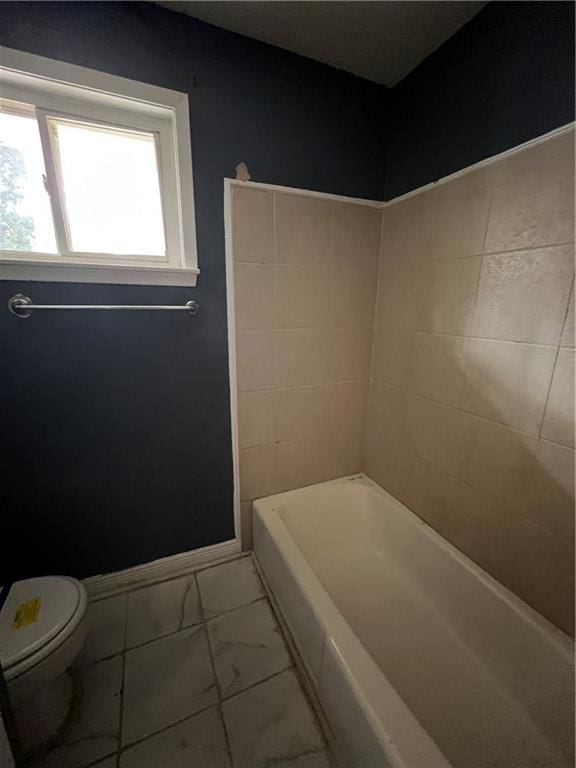 bathroom featuring tile patterned flooring, a tub, and toilet