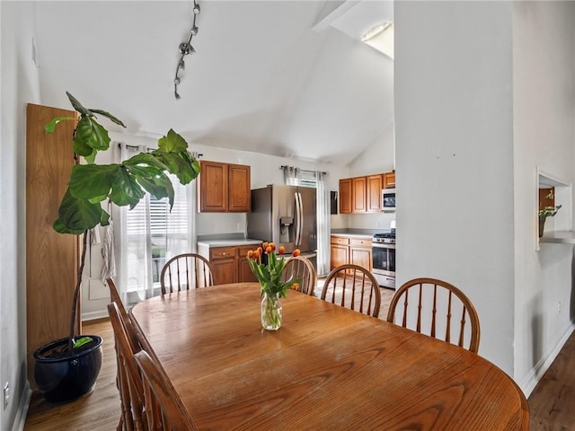 dining room with high vaulted ceiling, light wood-type flooring, and rail lighting