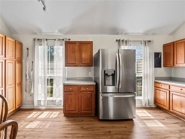 kitchen featuring a wealth of natural light, vaulted ceiling, and stainless steel fridge with ice dispenser