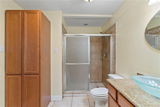 bathroom with tile patterned flooring, a shower with door, toilet, and vanity