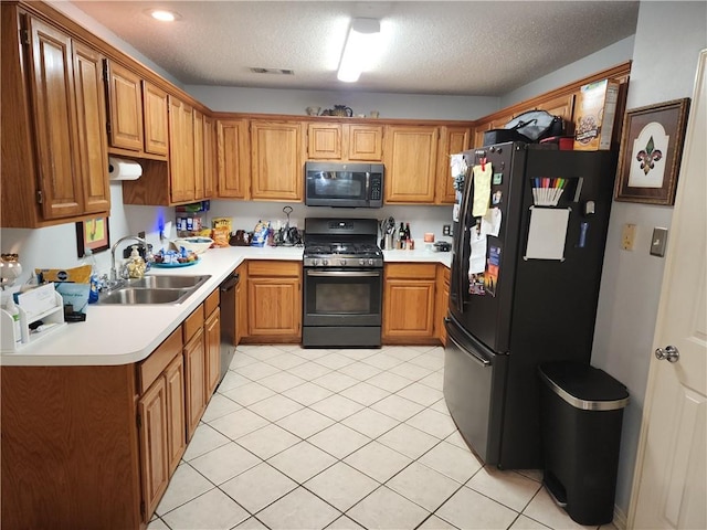 kitchen featuring a textured ceiling, black appliances, sink, and light tile patterned floors