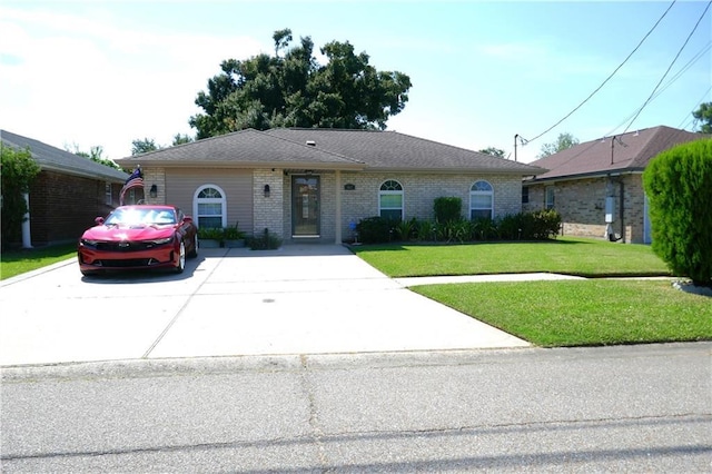 single story home featuring brick siding, concrete driveway, and a front yard