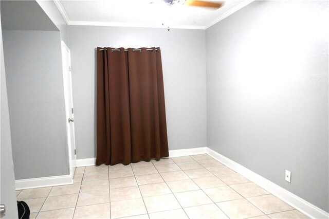 unfurnished room with a ceiling fan, light tile patterned flooring, crown molding, and baseboards