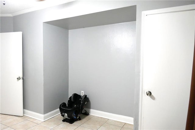 interior space featuring baseboards, crown molding, and light tile patterned flooring