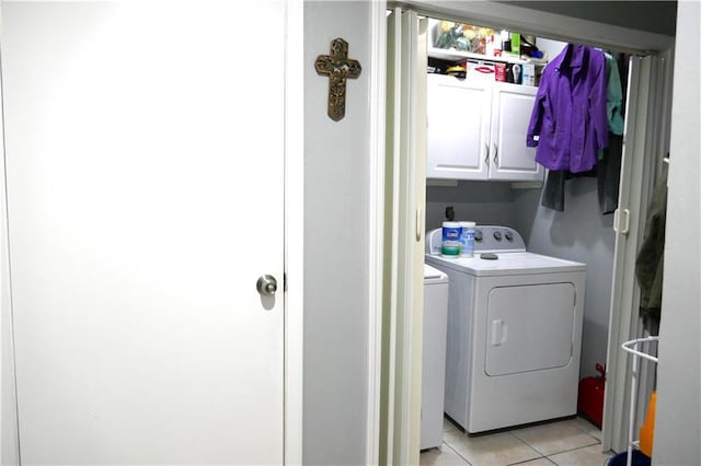 laundry room with light tile patterned floors, washer and clothes dryer, and cabinet space