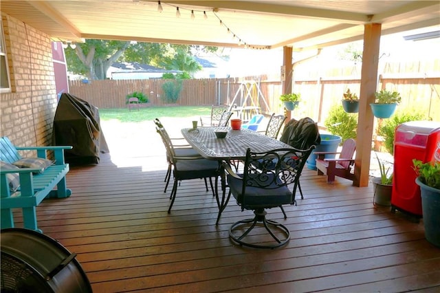 wooden deck with a fenced backyard, a grill, and outdoor dining area