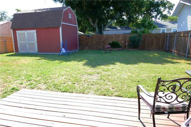 view of yard featuring a fenced backyard, a storage unit, a wooden deck, and an outbuilding