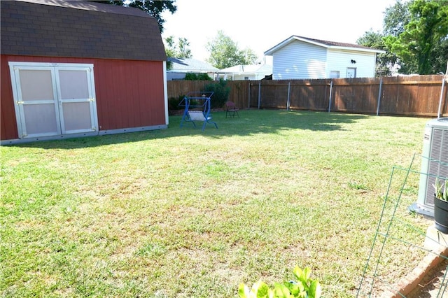 view of yard featuring central air condition unit, a storage shed, a fenced backyard, and an outbuilding