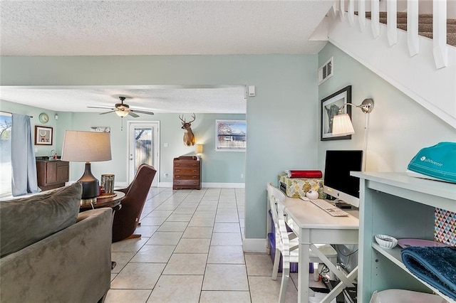 living room with a textured ceiling, ceiling fan, and light tile patterned flooring