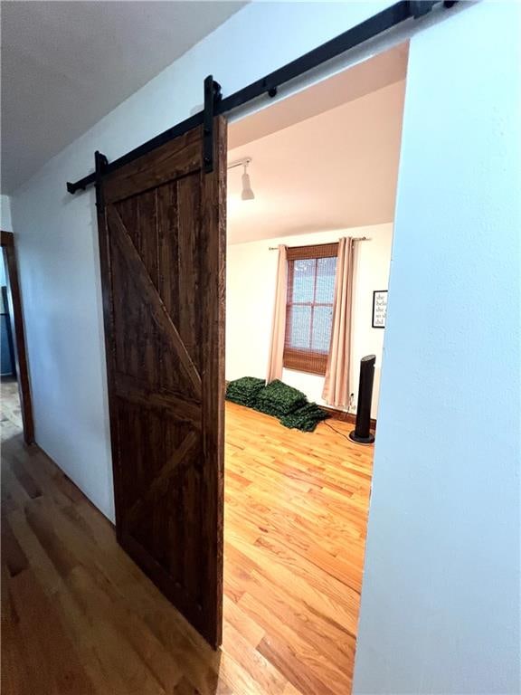 hall featuring a barn door and wood-type flooring