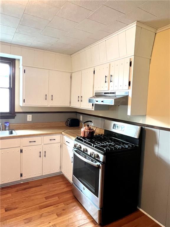 kitchen featuring white cabinetry, gas range, sink, and light hardwood / wood-style flooring