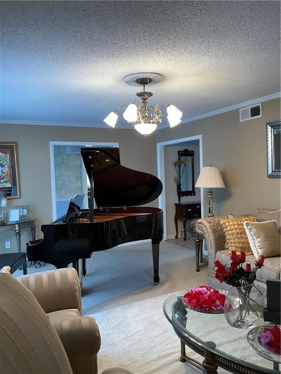 sitting room featuring carpet, visible vents, a chandelier, and a textured ceiling