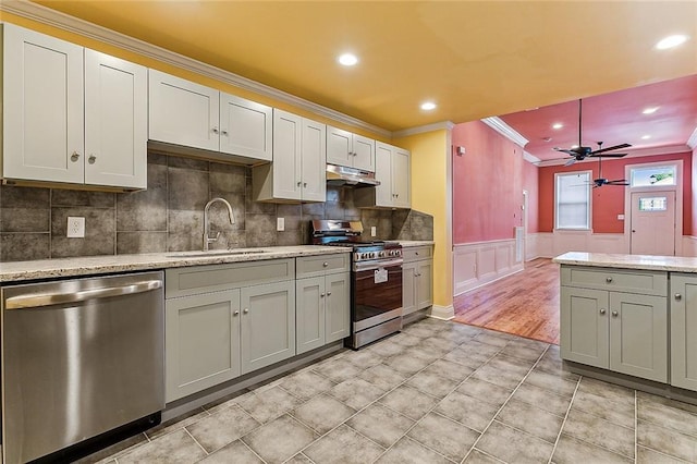 kitchen featuring light wood-type flooring, appliances with stainless steel finishes, tasteful backsplash, ceiling fan, and crown molding