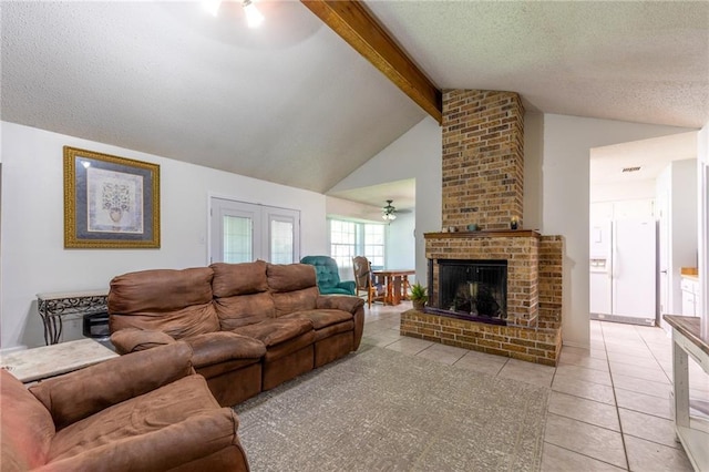 living room featuring a fireplace, beam ceiling, a textured ceiling, light tile patterned floors, and brick wall