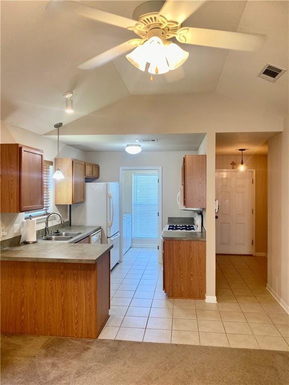 kitchen featuring visible vents, brown cabinetry, a peninsula, light countertops, and a sink