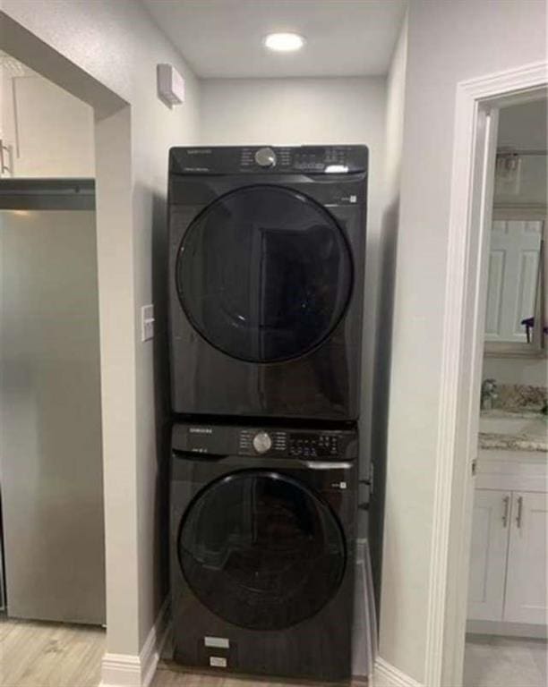 washroom featuring sink, stacked washer and dryer, and light wood-type flooring