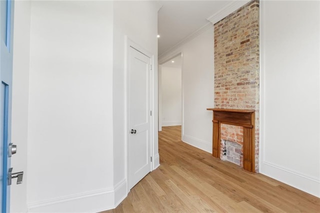 corridor with light hardwood / wood-style floors, brick wall, and ornamental molding