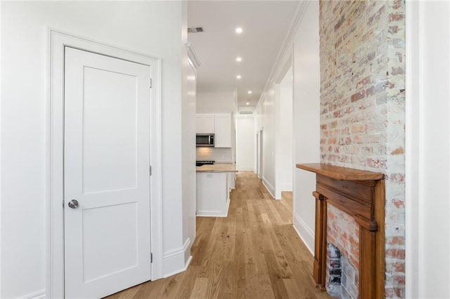 hallway featuring light hardwood / wood-style floors and ornamental molding