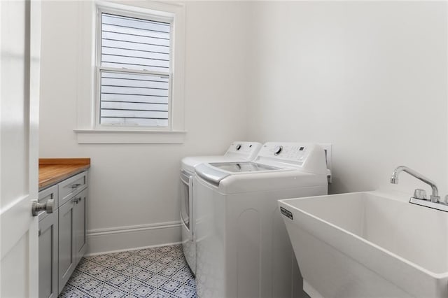 clothes washing area featuring sink, washing machine and dryer, light tile patterned flooring, and cabinets