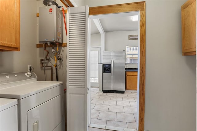 2546 Elder St, New Orleans, LA 70122 - clothes washing area with tankless water heater, cabinet space, light tile patterned floors, and washer and dryer