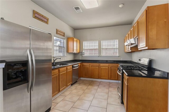 kitchen with appliances with stainless steel finishes, a wealth of natural light, light tile patterned floors, and sink