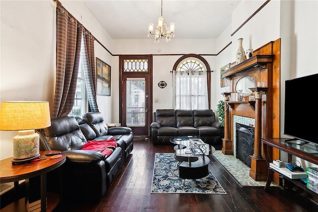 living room with a fireplace, dark wood-type flooring, and a chandelier