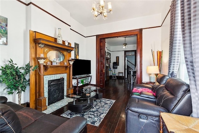 living room featuring a tiled fireplace, dark hardwood / wood-style flooring, and an inviting chandelier