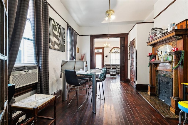 dining area with an inviting chandelier, a tiled fireplace, dark wood-type flooring, and cooling unit