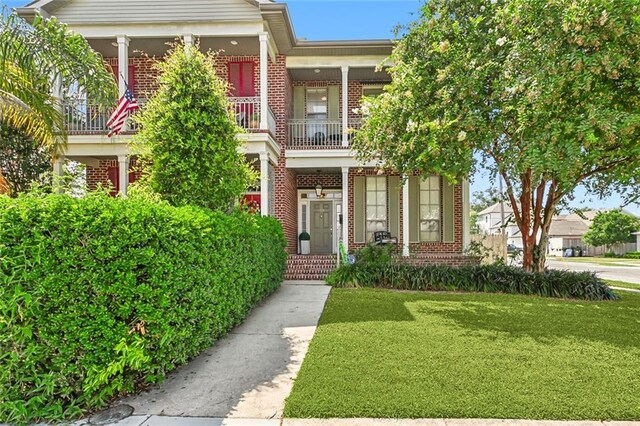 view of front of house with a balcony and a front lawn