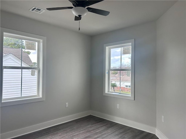 spare room featuring a wealth of natural light, dark hardwood / wood-style floors, and ceiling fan