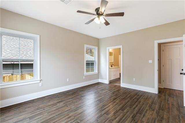 unfurnished bedroom with ceiling fan, dark wood-type flooring, multiple windows, and ensuite bathroom