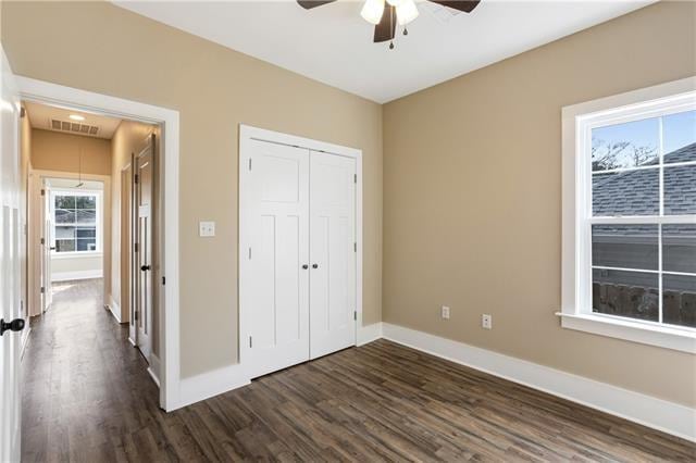 unfurnished bedroom featuring ceiling fan, dark hardwood / wood-style floors, and a closet