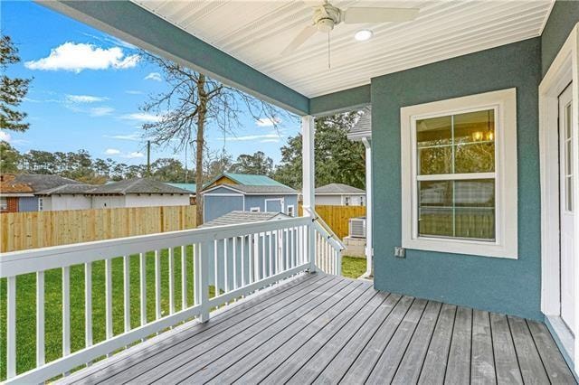 wooden deck with ceiling fan, an outdoor structure, and a yard